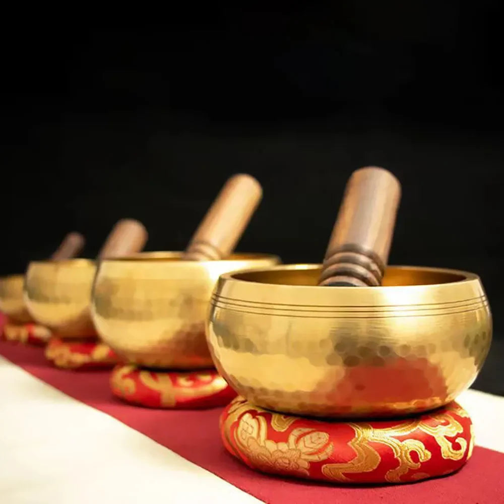 Set of gold singing bowls on a red mat with a dark background