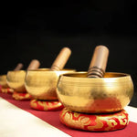Load image into Gallery viewer, Set of gold singing bowls on a red mat with a dark background
