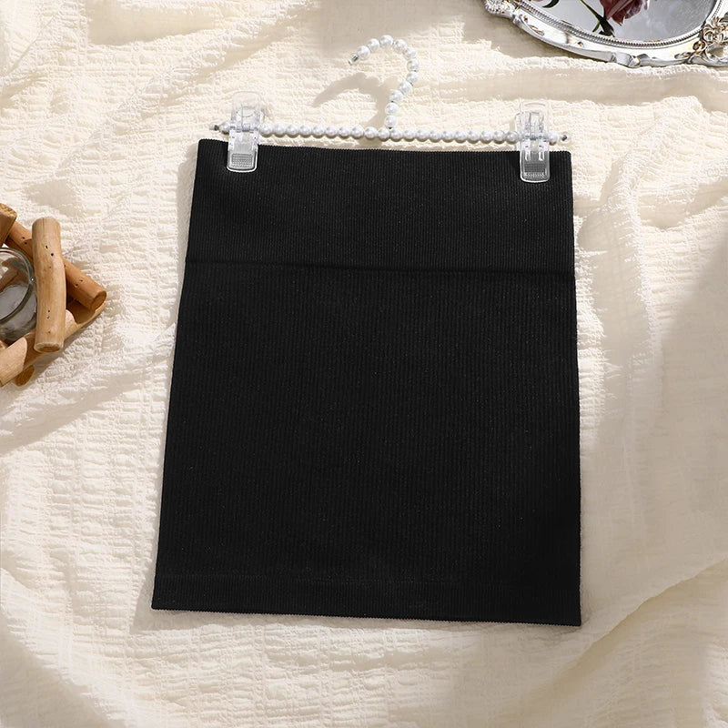 Black skirt on a hanger against a textured white background