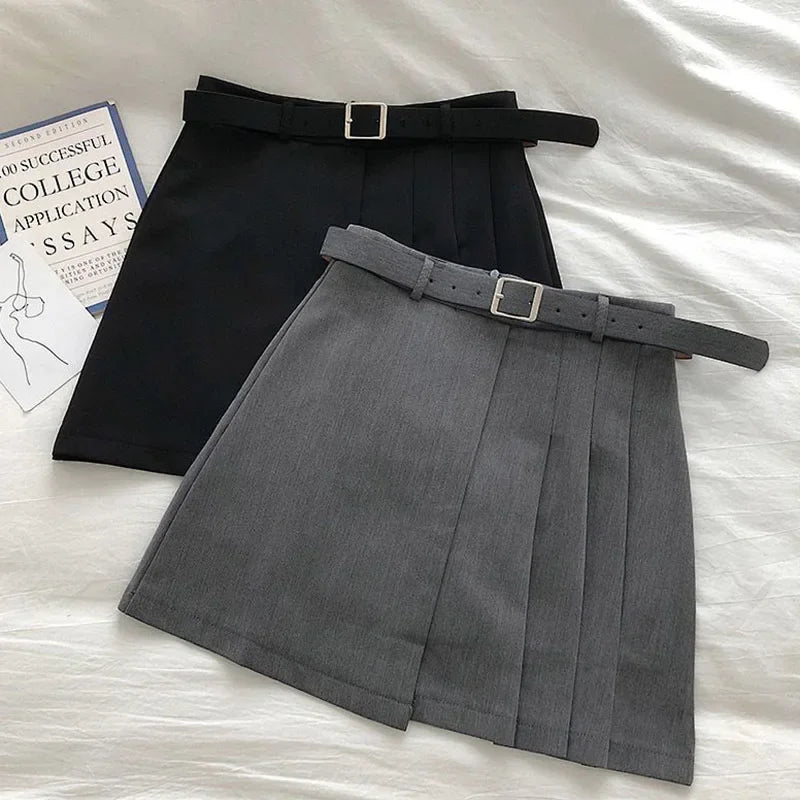 Black and gray pleated skirts with belts on a white surface