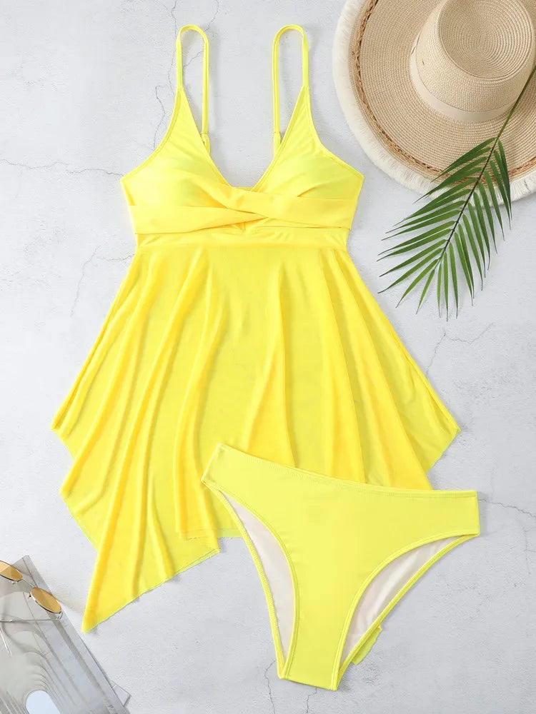 Yellow swimsuit with matching bottom, straw hat, and palm leaf on a light gray background
