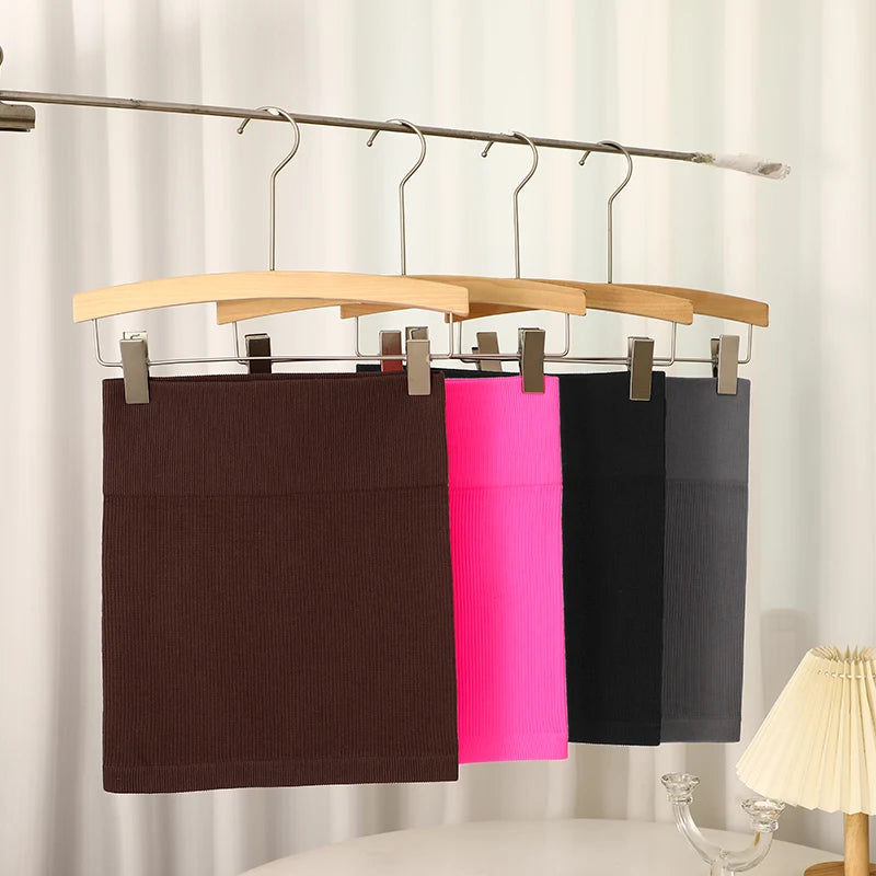 Three pairs of pants hanging on a wooden hanger against a neutral background.